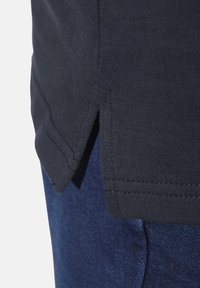 Navy cotton t-shirt with side slits and visible stitching detail, paired with dark blue denim fabric, showcasing texture contrast.