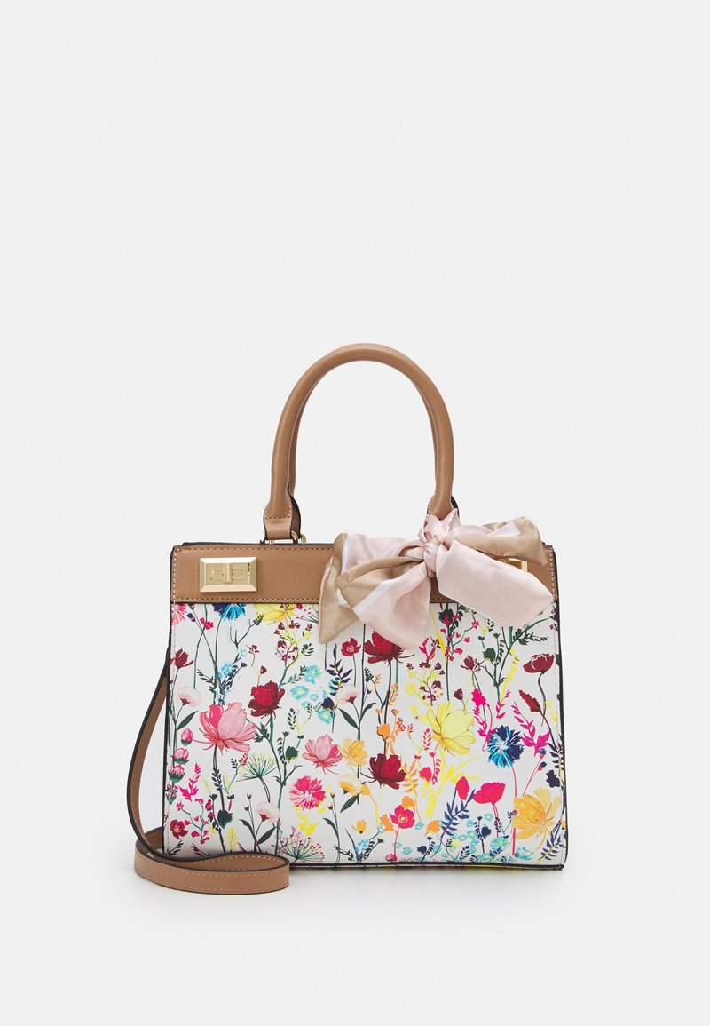 Sac à main avec poignées et bandoulière marron, corps blanc avec imprimé floral coloré, et un nœud rose et beige noué sur une des poignées.