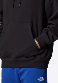 Zwarte hoodie met een kangoeroezak, verstelbare trekkoorden, ribgebreide manchetten en zoom. Gecombineerd met blauwe sweatpants met een logo.