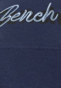 Navyblauwe sweatshirtstof met ribbelstructuur, voorzien van een geborduurd "Bench" logo in lichtblauw en vet zwart schrift.
