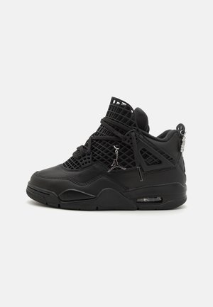 Basket de sport montante noire avec des panneaux en mesh, semelle à air visible, fermeture à lacets à l'avant, et petit pendentif métallique avec logo Jumpman suspendu aux lacets.