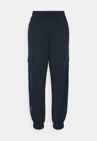 Marina joggerbyxor med dragsko i midjan, avsmalnande fållar och sidofickor med cargo-design som har en kontrasterande satinliknande panel.