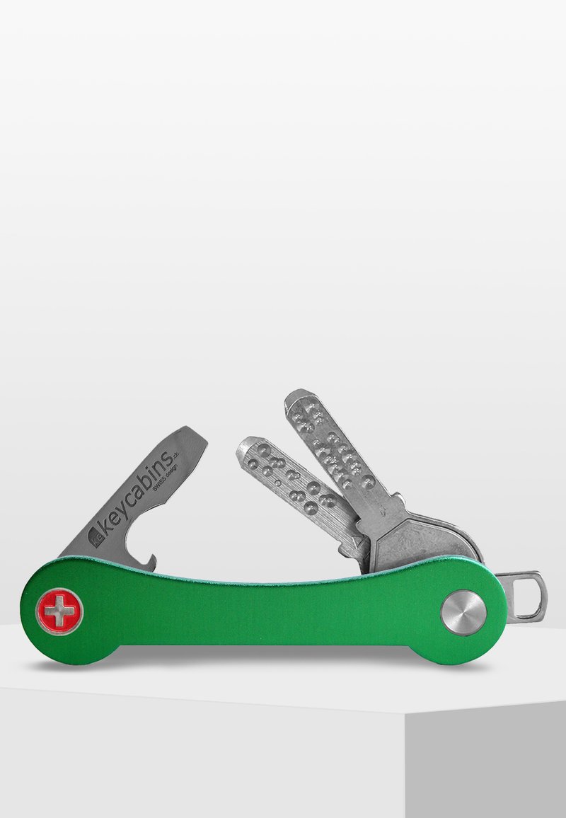 Multiverktygsnyckelorganisatör med grön aluminiumkropp, verktyg i rostfritt stål och en röd schweizisk kors-emblem; har olika nyckelformer och -designer.