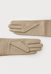 Beige lærhansker med tre fingeråpninger og en glatt tekstur, med ekstra polstrede detaljer på baksiden for komfort.