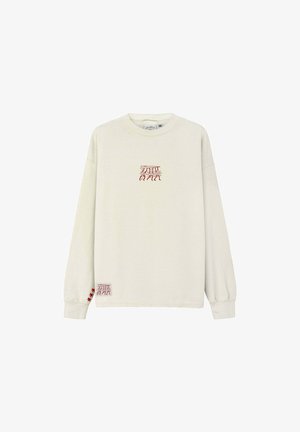 Jasnobeżowa bluza wykonana z miękkiego materiału. Posiada długie rękawy, okrągły dekolt oraz czerwone haftowane akcenty na piersi i rękawie.