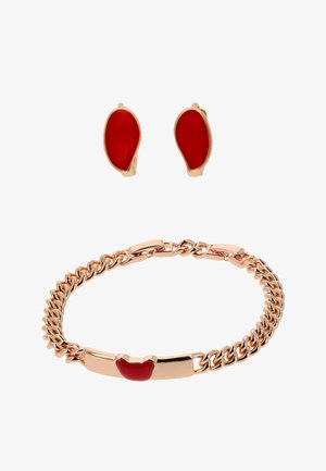 Goudkleurige armband en oorbellen set met gladde, roodkleurige, onregelmatig gevormde emaille details op een witte achtergrond.