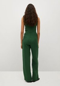 Un combinaisons sans manches vert avec un corsage ajusté, un pantalon large, un tissu texturé et un design de dos sans couture, vu de derrière.