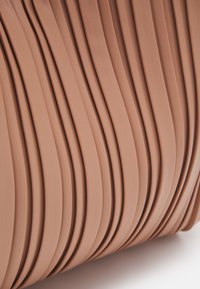 Tessuto plissettato in un delicato colore pesca, caratterizzato da texture ondulate e superfici lisce per un aspetto elegante.