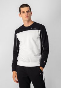 Sudadera de cuello redondo en negro y gris que cuenta con puños de canalé, un corte atlético y un logo bordado en el pecho. Material suave de mezcla de algodón.