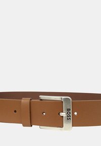 Cintura in pelle marrone con una fibbia rettangolare in argento che presenta la parola "BOSS". Texture liscia e vestibilità regolabile con diversi fori.