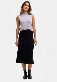 Graues ärmelloses Oberteil kombiniert mit einem schwarzen knöchellangen Rock; glatte Textur, taillierte Silhouette, schlichtes Design und flache schwarze Schuhe.