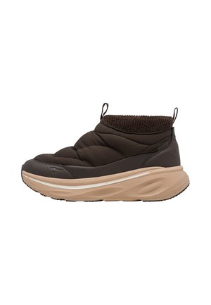 Chaussure marron matelassée à enfiler avec languettes, semelle épaisse beige et col de cheville tricoté, montrée de profil sur fond blanc.