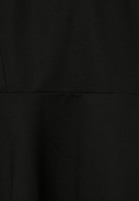 Tissu noir avec une texture lisse, présentant un corsage ajusté qui se transforme en une jupe évasée ; design minimal sans motifs ni accessoires visibles.