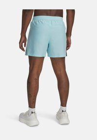 Shorts de sport bleu clair avec une taille élastique. Présente des accents latéraux noirs contrastants et une texture lisse. Baskets blanches portées.