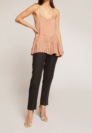 Camisola rosa chiaro con pieghe e spalline sottili, orlo peplum a strati. Abbinata a pantaloni neri su misura e sandali gialli con doppia fascia.