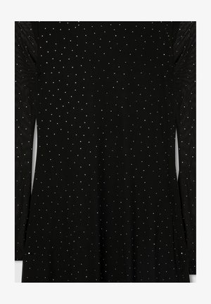 Indumento nero con maniche lunghe, realizzato in un materiale testurizzato decorato con piccoli chiodini metallici disposti in un motivo sparso.