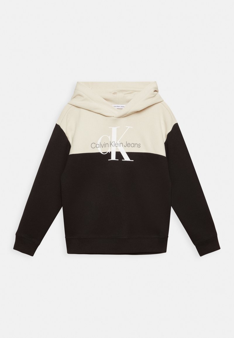Felpa con cappuccio caratterizzata da una parte superiore crema e una parte inferiore nera, con il logo "Calvin Klein Jeans" in bianco sul petto. Materiale morbido.