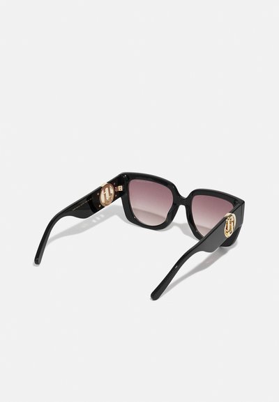 Schwarze Sonnenbrille im Cat-Eye-Design, mit getönten Gläsern und goldenen Logoakzenten an den Bügeln. Elegantes Design mit glänzender Textur.