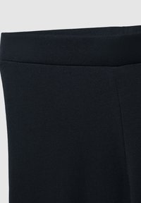 Zbliżenie czarnych legginsów z materiału ukazujące gładką teksturę i szeroki elastyczny pas.