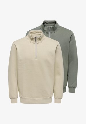 Zwei gefaltete Sweatshirts mit Viertel-Reißverschluss, eines beige vorne und eines gedämpft grün dahinter, beide mit gerippten Bündchen und Kragen.