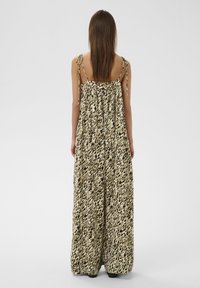 Robe maxi à imprimé léopard beige et noir. Bretelles spaghetti réglables, dos froncé, tissu fluide et jambes larges.