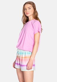 Camiseta de manga corta rosa combinada con pantalones cortos de tie-dye en tonos pastel que presentan rayas en azul, naranja, rosa y blanco, con cintura elástica y cordón.