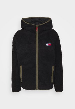 Czarna polarowa kurtka zapinana na zamek z kapturem, oliwkowymi lamówkami, przednimi kieszeniami oraz logo Tommy Jeans na piersi.