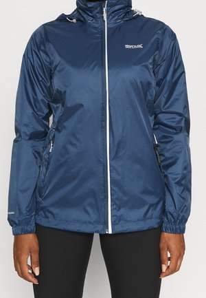 Marineblaue wasserdichte Jacke mit weißem Reißverschluss, Regatta Great Outdoors-Logo, elastischen Bündchen und Kapuze, getragen über einer schwarzen Hose.