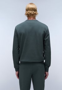 Felpa verde scuro realizzata in tessuto morbido, presenta un colletto girocollo, polsini e orlo a costine, con un design minimalista e una texture liscia.