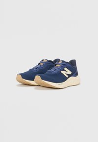 Navy mesh sneakers with beige accents, featuring a cushioned sole and a prominent white "N" logo on the side. Textured rubber outsole.