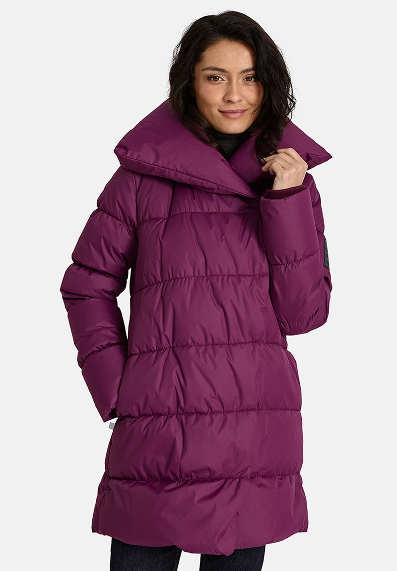 Violeta pūkaina mētelis ar augstu apkakli, kuram ir quilted raksts un redzami šuvumi. Materiāls izskatās gluds un spīdīgs.