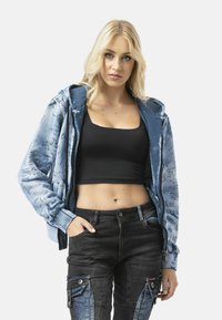 Light blue hoodie with text pattern, zipper front, and drawstring hood; paired with black cargo pants featuring blue denim accents.