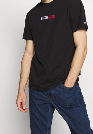 Czarny bawełniany t-shirt z wyhaftowanym logo "TOMMY JEANS" w kolorach czerwonym, białym i niebieskim. Krótkie rękawy i okrągły dekolt, w połączeniu z dżinsami.