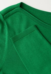 Pull en tricot vert avec col et poignets côtelés, présentant une texture lisse. Gros plan montrant les détails des coutures et du motif du tissu.