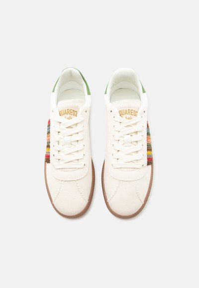 Paire de baskets basses blanches avec semelles marron, accents verts au talon et tissu rayé multicolore sur les côtés, vues de dessus.