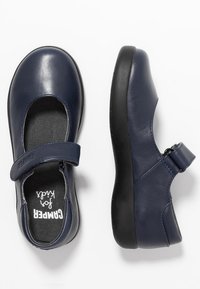 Zapatos Mary Jane de cuero azul marino con punta redonda, correa ajustable, suela de goma negra y un forro interior suave para mayor comodidad.