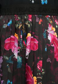 Falda plisada con una base negra que presenta vibrantes patrones florales y de mariposas en rosa, azul y verde. Cintura elástica con detalle de marca.