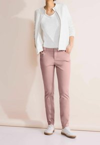 Bílá zipová bunda, bílá košile, růžové kalhoty a bílé tenisky. Bunda má příbroušenou texture a kalhoty mají akcent v podobě přední kapsy.