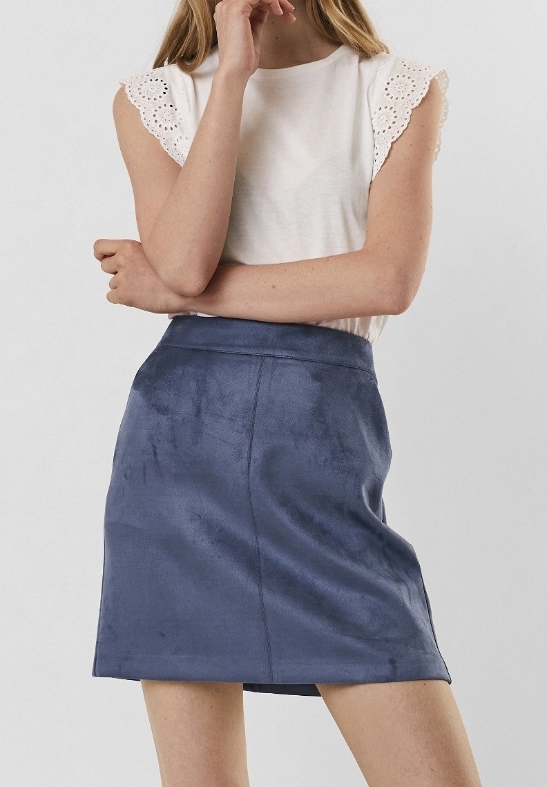 White top with eyelet trim sleeves and a dark blue, soft-textured mini skirt. The skirt features a smooth surface and fitted silhouette.