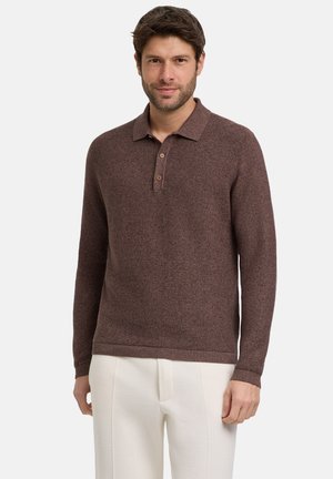 Brauner Langarm-Polo-Pullover mit strukturiertem Strick, einer dreiknöpfigen Knopfleiste und gerippten Bündchen, kombiniert mit weißen Hosen.