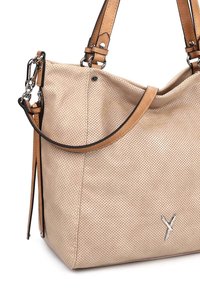 Sac seau beige perforé avec des anses en cuir brun clair, quincaillerie métallique, et un petit logo argenté en forme de Y sur le devant.