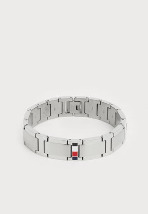 Metalarmbånd med sammenkoblede lenker, med en polert og børstet sølvfinish. Små røde, hvite og blå detaljer på låsen.