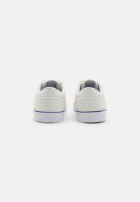 Sapatilhas de lona brancas com biqueiras redondas, colares almofadados e uma sola roxa. Apresentam uma textura suave e um design minimalista com realces laranja.