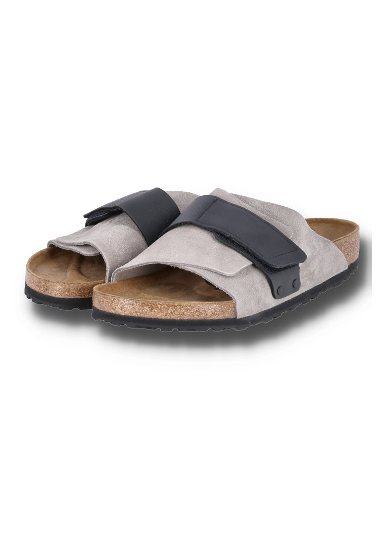 Hellgraue Wildledersandalen mit einem schwarzen Klettverschlussriemen und einem Korkfußbett. Mit einer strukturierten Gummisohle für besseren Halt.