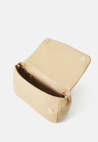 Beige synthetic handbag with a glossy finish, featuring a magnetic snap closure, inside zip pocket, and minimalistic design.