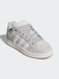 Grå semsket sneakers med hvite lærstriper, rund tå, teksturert overdel og grå lisser. Gummisåle med en kontrasterende lys brun såle.