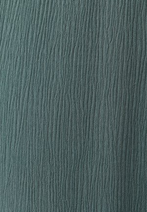 Gros plan d’un tissu avec des côtes texturées verticales dans une couleur vert-gris atténuée.