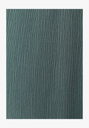 Gros plan d’un tissu avec des côtes texturées verticales dans une couleur vert-gris atténuée.