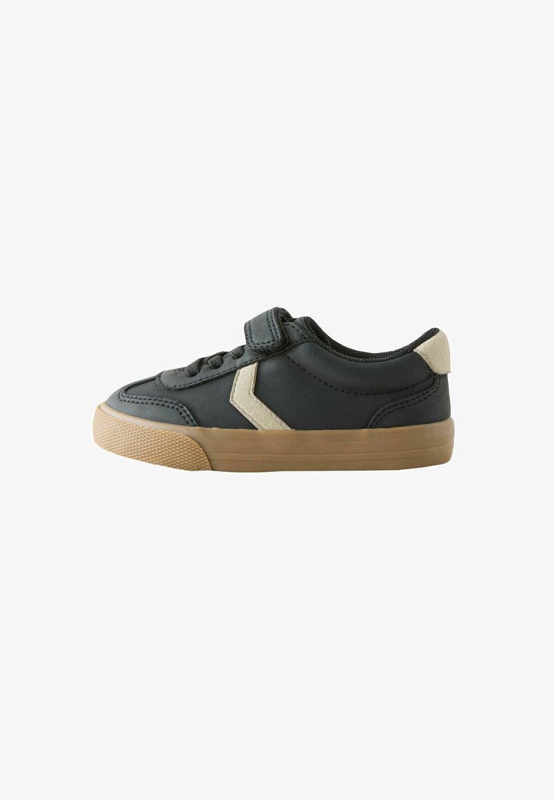 Sneaker nera con cinturino in velcro e lacci, caratterizzata da un accento beige sul lato e una suola in gomma testurizzata.