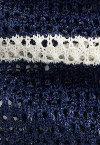 Mörkblå stickad tyg med en vit spetsdetalj. Texturen är öppen och luftig, med en mix av tighta och lösa stygn.